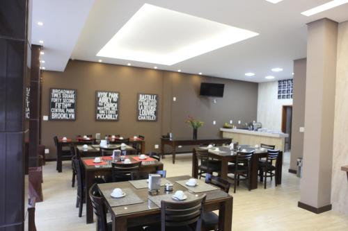 HOTEL ALVORADA في Leopoldina: غرفة طعام مع طاولات وكراسي وتلفزيون