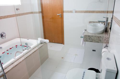 a bathroom with a tub and a toilet and a sink at Hotel Roari in Cuiabá