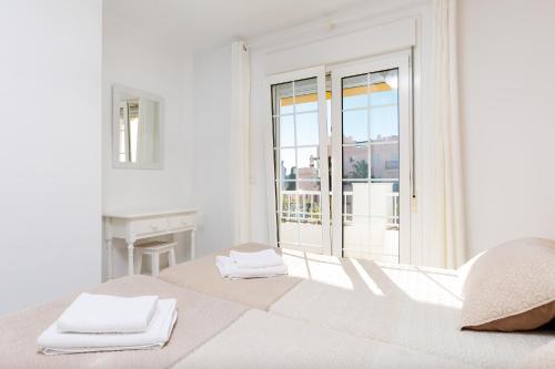 a white bedroom with a bed with towels on it at AT Almoraide Rooms Suites in Nerja