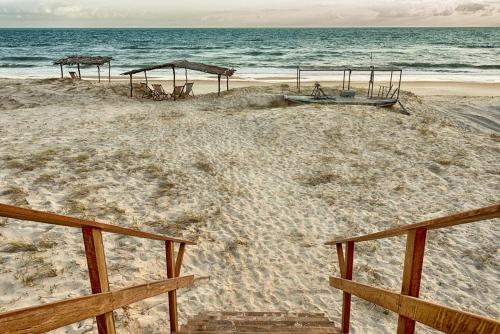 a beach with a boat and umbrellas and the ocean at Bruno Marambaia Charme Hotel in Beberibe