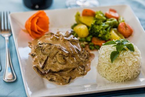 a plate of food with meat and rice and vegetables at Bruno Marambaia Charme Hotel in Beberibe