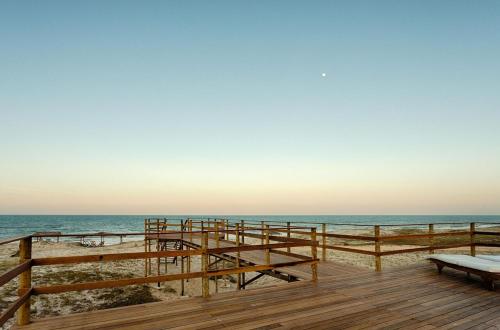 a wooden pier with a bench on the beach at Bruno Marambaia Charme Hotel in Beberibe