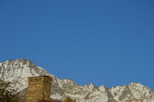 a brick tower in front of a mountain at Ailama Guesthouse in Mestia