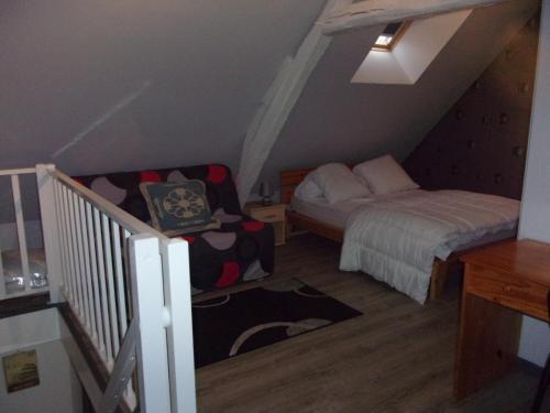 a small attic room with a bed and a chair at chez christophe in Beauchêne