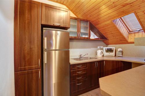 eine Küche mit einem Kühlschrank aus Edelstahl und Holzschränken in der Unterkunft Apartments Nový Život in Nový Život
