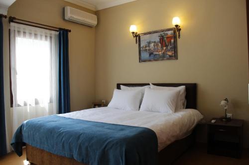 a bedroom with a bed with a blue blanket and a window at Utopia Lodge Hotel in Kayakoy