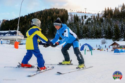 two people on skis shaking hands in the snow at Hotel La Baita in Folgaria