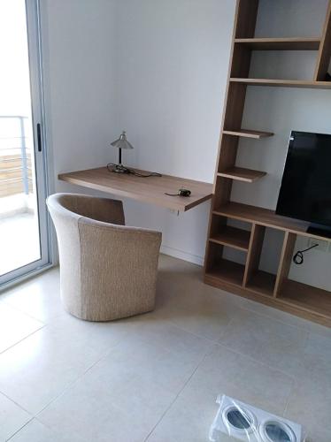 a room with a chair and a desk and a television at Garden 33 in Chivilcoy
