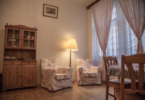 uma sala de estar com duas cadeiras e um candeeiro em Apartments Emma em Praga