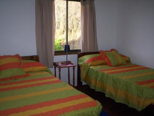 2 camas en una habitación con ventana en cabañas sector peñuelas en Coquimbo