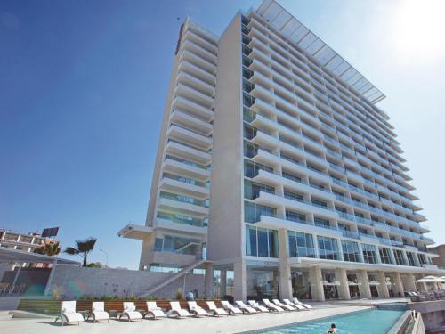 a large building with a pool in front of it at Terrado Suites Antofagasta in Antofagasta