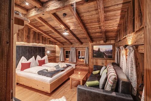 ein Schlafzimmer mit einem Bett und einem Sofa in einem Zimmer in der Unterkunft Highking Chalet Grünegg in Dienten am Hochkönig