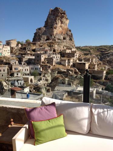 a couch with colorful pillows sitting in front of a mountain at Hezen Cave Hotel in Ortahisar