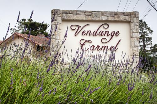 een bord voor een tuin met paarse bloemen bij The Vendange Carmel Inn & Suites in Carmel