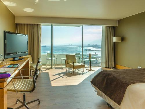 a hotel room with a bed and a view of the ocean at Terrado Suites Antofagasta in Antofagasta