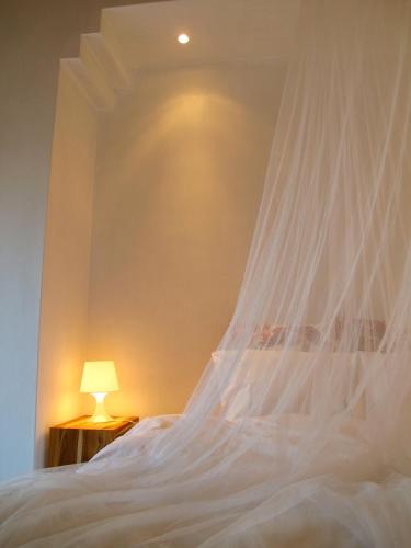 a bed with a white canopy and a lamp at Tres Marias in Vila Nova de Milfontes
