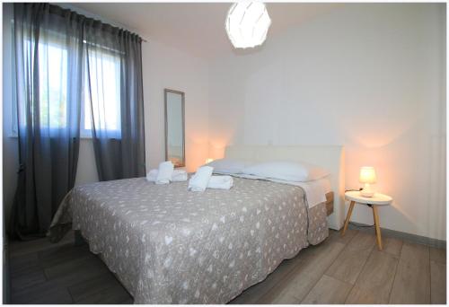 um quarto branco com uma cama e uma janela em Apartments Silver Beauty em Rogoznica