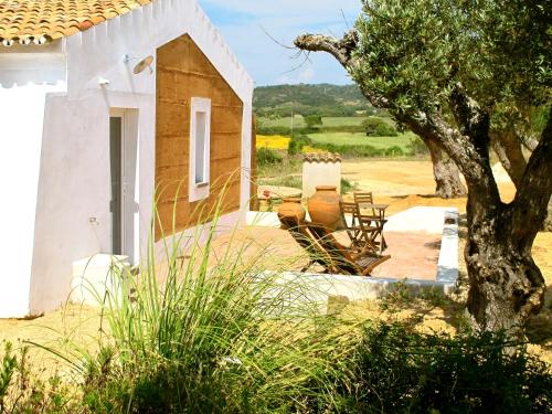 a house with chairs and a tree in front of it at Tres Marias in Vila Nova de Milfontes