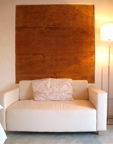 a white couch in a room with a wooden wall at Tres Marias in Vila Nova de Milfontes