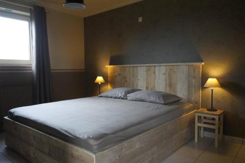a bedroom with a large bed with a wooden headboard at Kampenhof in Maaseik