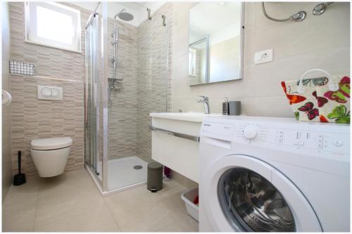 a white washing machine in a bathroom with a shower at Apartments Silver Beauty in Rogoznica