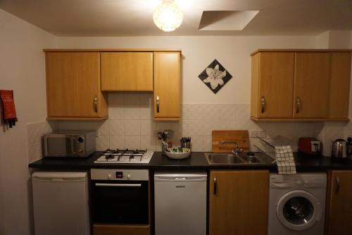a kitchen with wooden cabinets and a stove and a sink at The Coach House in Bristol