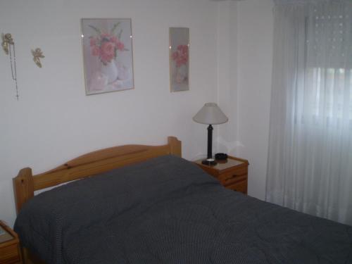 1 dormitorio con cama, lámpara y ventana en Depto. 2 ambientes en Mar del Plata