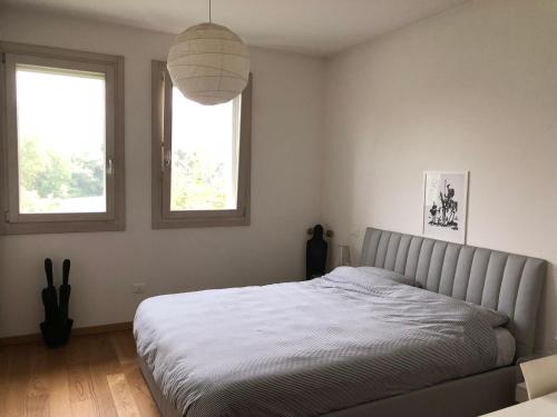 a bedroom with a bed and two windows at La stanza di Cesare in Treviso