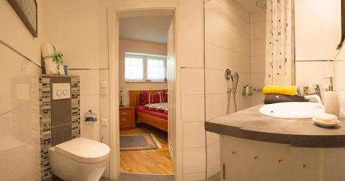 a bathroom with a toilet and a sink and a bedroom at Auszeit Flair der Provence in Hausen
