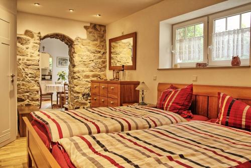 a bedroom with two beds and a stone wall at Auszeit Flair der Provence in Hausen