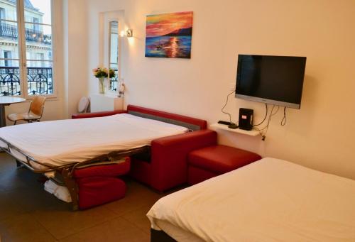 um quarto de hotel com duas camas e uma televisão de ecrã plano em Studio Fontaine Des Innocents em Paris