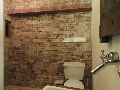 a bathroom with a toilet and a stone wall at Casa del Temezcuitate in Guanajuato
