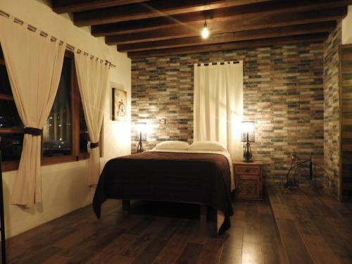 a bedroom with a bed and a brick wall at Casa del Temezcuitate in Guanajuato