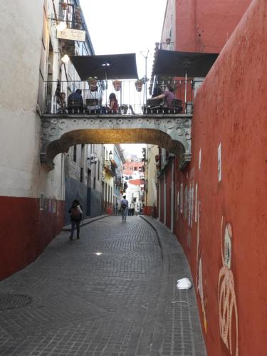 an alley with a bridge with people sitting on top at Casa del Temezcuitate in Guanajuato