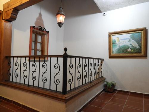 a hallway with a stair railing and a painting on the wall at Casa del Temezcuitate in Guanajuato