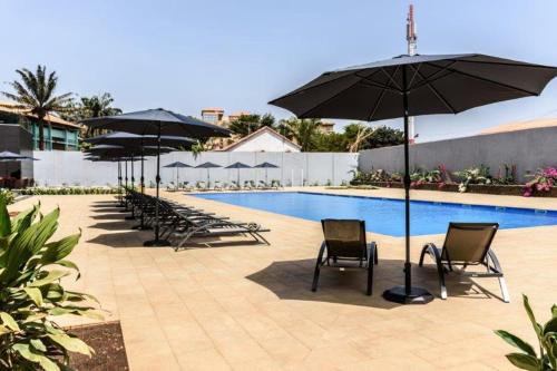 a group of chairs and umbrellas next to a pool at Ceiba Hotel Bissau in Bissau