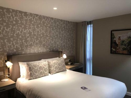 a bedroom with a large white bed with two lamps at Edgbaston Park Hotel Birmingham in Birmingham