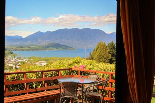 a table and chairs on a balcony with a view of a lake at Cabañas Parque Del Lago in Panguipulli