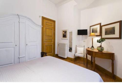 a bedroom with a white bed and a desk and a chair at Alba Home in Palermo