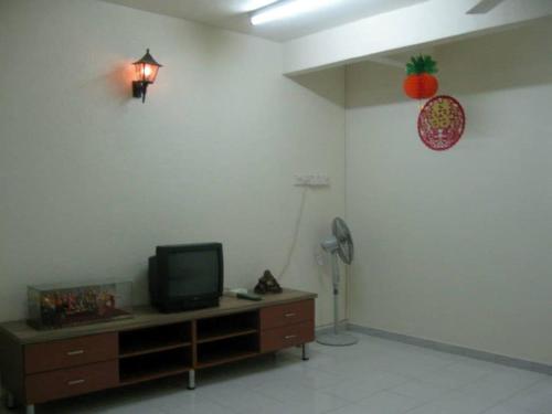 a living room with a tv on a cabinet and a pineapple on the wall at Yong Homestay in Kuala Perlis