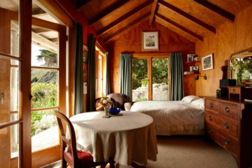ein Schlafzimmer mit einem Bett und einem Tisch in einem Zimmer in der Unterkunft Te Hapu Coastal Cottages in Collingwood