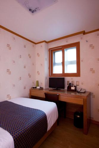 a bedroom with a bed and a desk with a computer at Hotel Daewoo Inn in Seoul