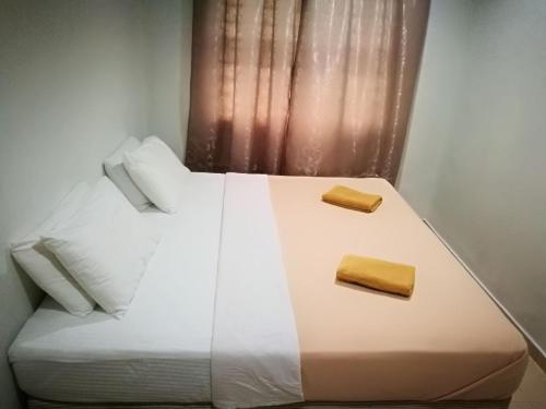 a white bed with two pillows and a window at One Homestay @ Kirana in Kuala Berang