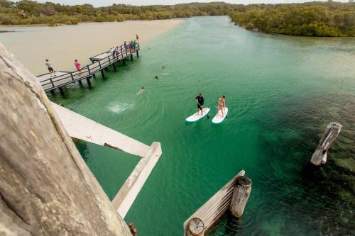 two people on surfboards in the water near a pier at NRMA South West Rocks Holiday Park in South West Rocks
