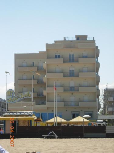 a large building on the beach with umbrellas in front of it at Hotel San Francisco Spiaggia in Rimini