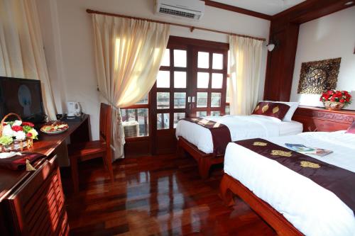 a hotel room with two beds and a desk with flowers on it at Manorom Boutique Hotel in Vientiane