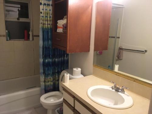 ein Badezimmer mit einem Waschbecken, einem WC und einem Spiegel in der Unterkunft Sandy's House in Vancouver