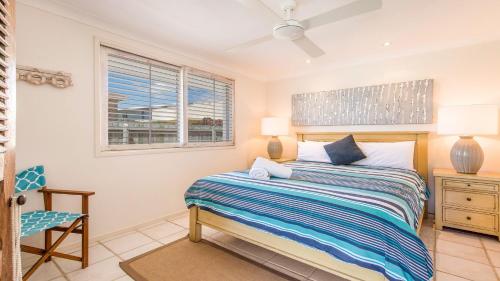 a bedroom with a bed and a chair and a window at Barefoot in Lennox- Beachfront Pool in Lennox Head