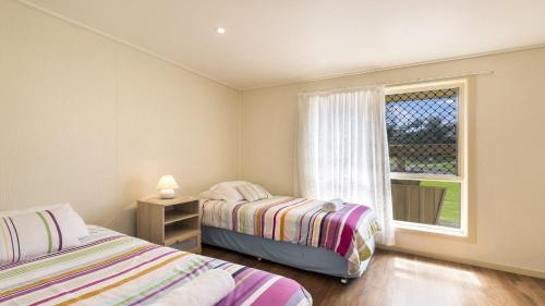 two beds in a room with a window at Haere Mai 2 in East Ballina