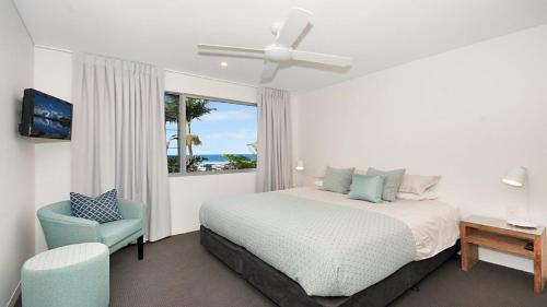 a bedroom with a bed and a chair and a window at Vista in Lennox Head